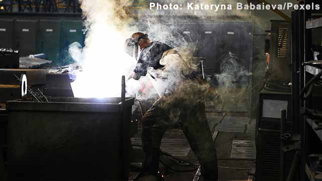 Man Wearing Welding Mask Covered in Welding Smokes