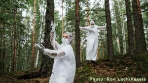 Two Person Wearing White Hazmat Suits in the Woods